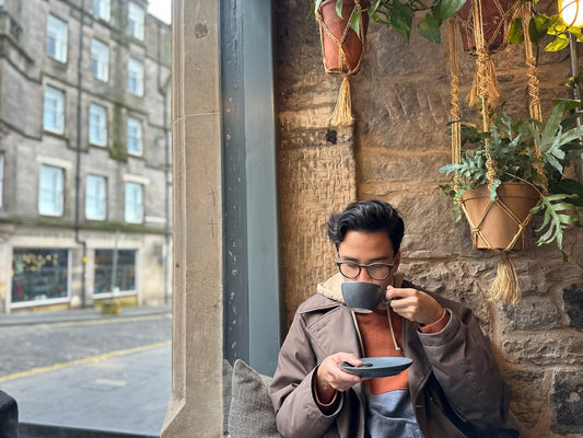 Phelan in a coffee shop near a window drinking tea